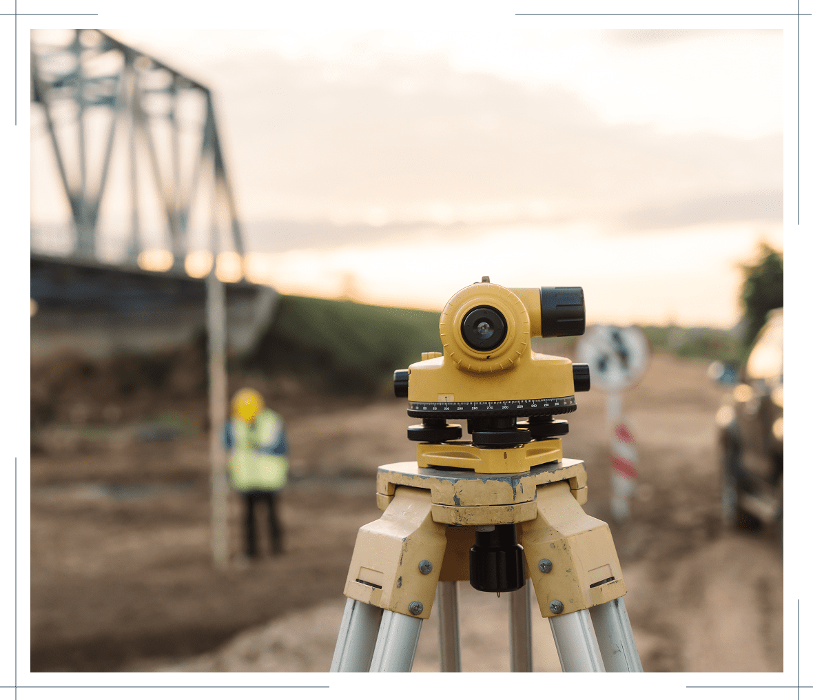 Surveying equipment on construction site near bridge.