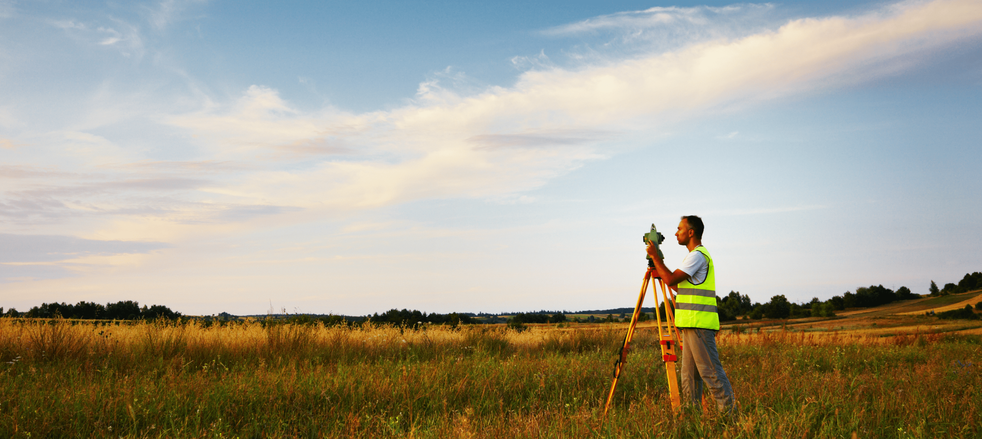 Surveyor working in a grassy field.